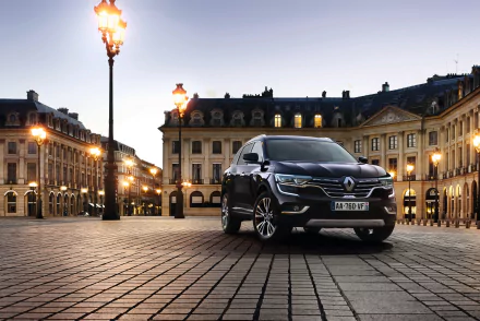 Renault Koleos SUV parked on a cobblestone plaza at dusk, illuminated by streetlamps with ornate city buildings — 4K Ultra HD PC desktop wallpaper background vehicle.