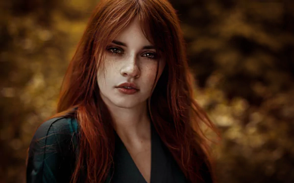 A captivating redhead woman with brown eyes and freckles gazes confidently at the camera, set against a soft, blurred background. An 8K Ultra HD image showcasing her striking features.