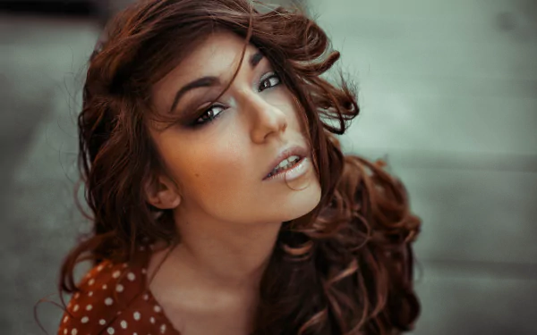 Close-up of a brunette model with brown eyes and wavy hair, captured in sharp detail for an 8K Ultra HD PC desktop wallpaper background.
