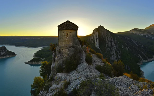 A stunning landscape of a fortress overlooking the Mare de Déu de la Pertusa lake in Spain, captured at sunrise, showcasing the natural beauty of the region.