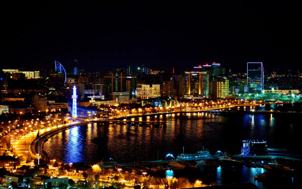 Night view of Baku's illuminated coastal cityscape in Azerbaijan, showcasing modern buildings and bright lights reflected on the water in stunning 4K Ultra HD quality.