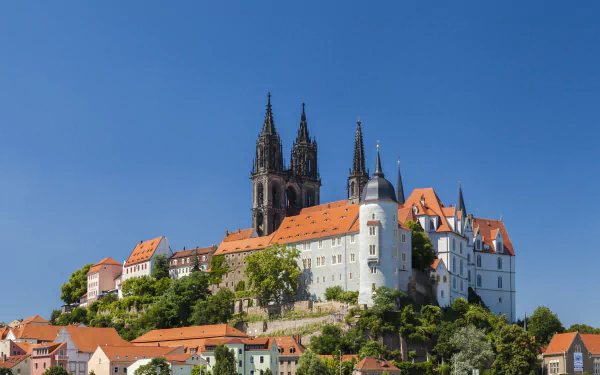 Meissen hilltop castle in Germany — a man-made fortress with red tile roofs and twin spires against a clear blue sky, 5K Ultra HD PC desktop wallpaper.