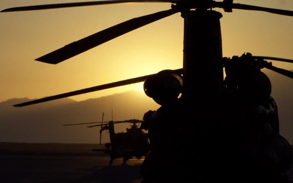 A stunning HD desktop wallpaper featuring military helicopters silhouetted against a glowing sunset, showcasing their powerful rotors and dynamic presence.