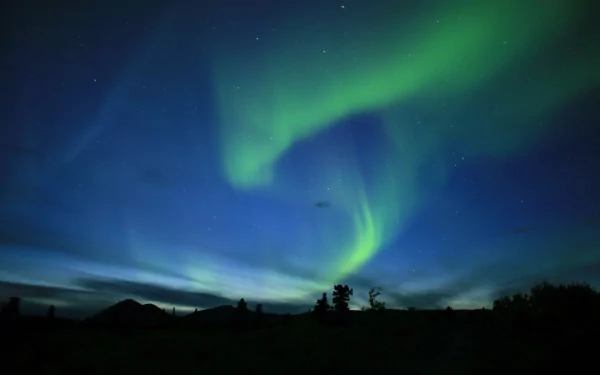 HD desktop wallpaper and background featuring a stunning display of the aurora borealis, with vibrant green and blue lights dancing in a night sky above a serene landscape.
