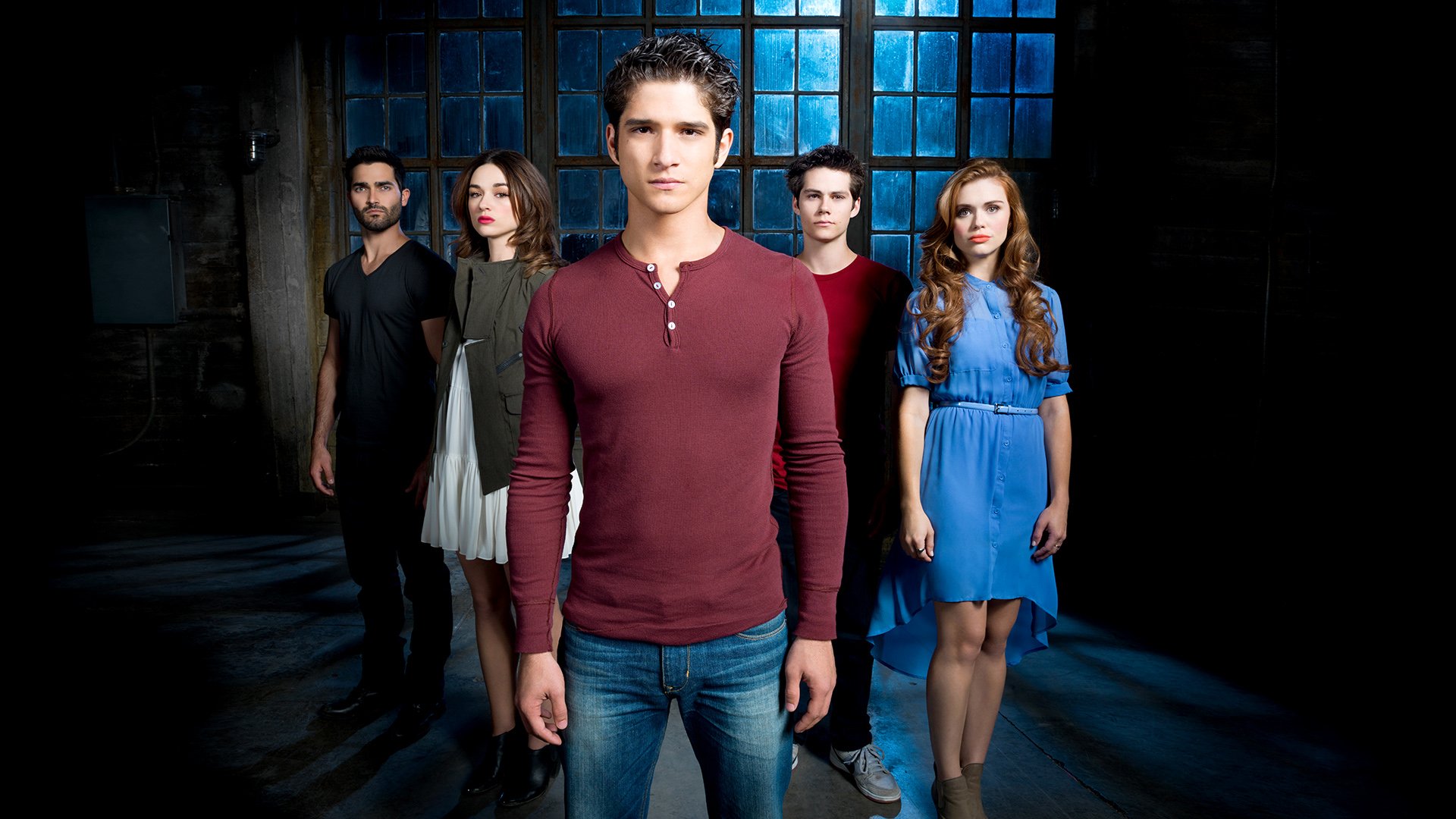 HD PC desktop wallpaper featuring the main cast of the Teen Wolf TV show standing in a dimly lit, industrial setting with blue window panes in the background.