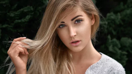 HD PC desktop wallpaper background: close-up of a blonde model woman's face with soft lighting and dark green foliage behind.