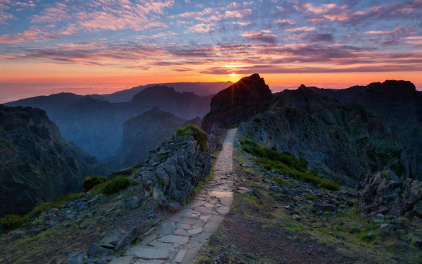 HD desktop wallpaper showcasing a man-made path winding through mountainous landscape in Portugal during a vibrant sunset.