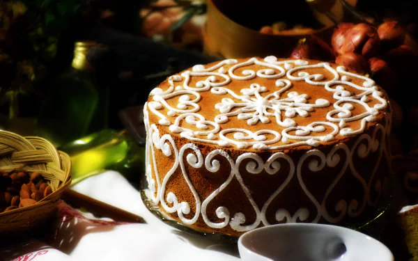 5K Ultra HD PC desktop wallpaper of a decorated pastry cake (food) with ornate white icing scrollwork, set on a table with nuts and a cup.