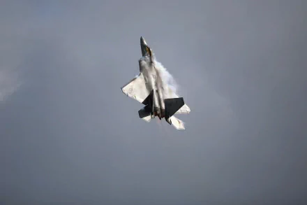 A dynamic Lockheed Martin F-22 Raptor performs a high-speed maneuver against a cloudy sky, showcasing the power and agility of the United States Air Force.