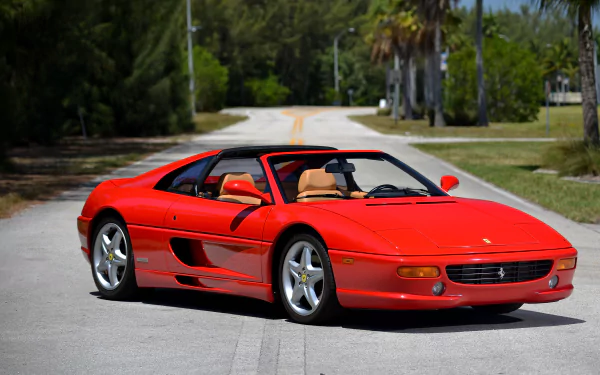 Red Ferrari F355 supercar parked on a sunny, tree-lined road. This 4K Ultra HD image showcases the sleek design of the iconic vehicle against a natural backdrop.
