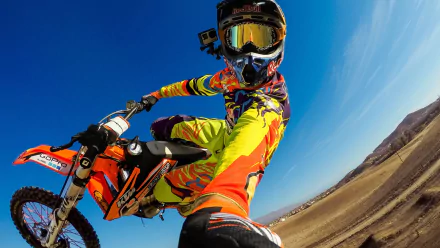 A dynamic motocross rider performs a jump against a clear blue sky, showcasing vibrant gear and a thrilling sense of speed, capturing the essence of sports in an HD desktop wallpaper.