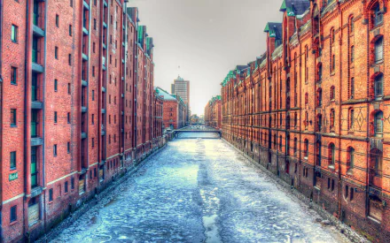 Winter scene of a frozen canal flanked by historic red brick buildings in Hamburg, Germany, captured in high definition as a striking PC desktop wallpaper.