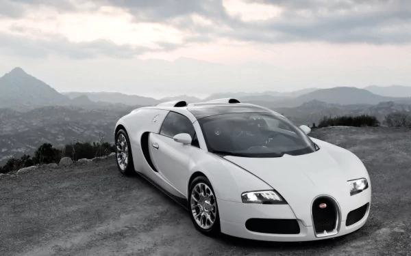 A stunning HD wallpaper showcasing a sleek white Bugatti parked on a rugged terrain with mountains in the background, emphasizing luxury and elegance in automotive design.