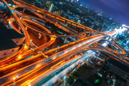 HD PC wallpaper: Japan's Osaka at night — time-lapse view of a glowing, man-made elevated highway interchange with streaking lights and city skyline.