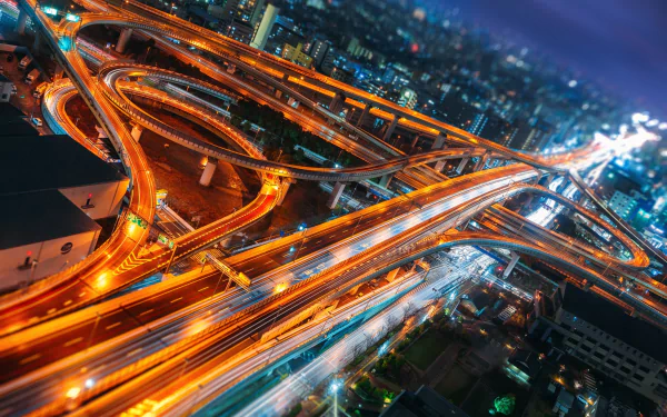 HD PC wallpaper: Japan's Osaka at night — time-lapse view of a glowing, man-made elevated highway interchange with streaking lights and city skyline.