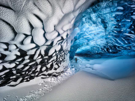 A stunning HD desktop wallpaper of a winter ice cave with snow-covered ground and intricate icy textures showcasing nature’s frozen beauty.