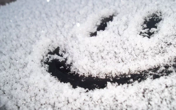 A snowy surface with a smiley face carved into the snow, creating a funny and cheerful HD desktop wallpaper and background.