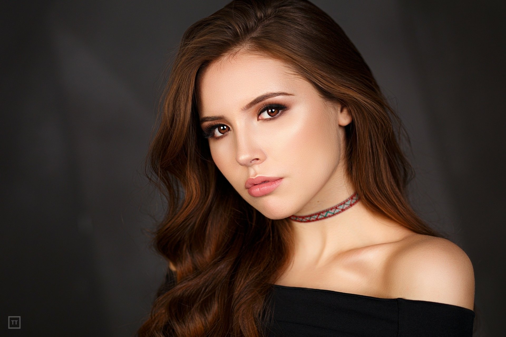 HD desktop wallpaper of a brunette woman with brown eyes and a model-like pose, set against a dark background.