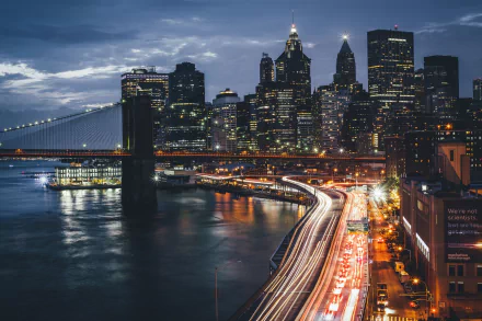 Nighttime HD desktop wallpaper showcasing the Brooklyn Bridge and Manhattan skyline with illuminated skyscrapers and light trails in New York City, USA.