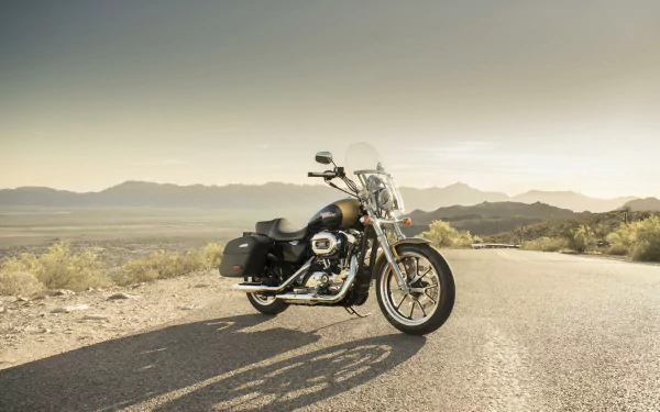 Harley-Davidson SuperLow 1200T motorcycle parked on a sunlit desert road with distant mountains — HD PC desktop wallpaper/background showcasing the Harley-Davidson SuperLow vehicle.