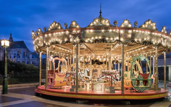 A brightly lit Parisian carousel with ornate horses and carriages against a twilight sky, captured in HD for a vivid desktop wallpaper background.