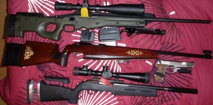 A collection of rifles including a .338 Lapua and a Ruger sniper rifle, showcased against a patterned backdrop, emphasizing man-made precision in target shooting.