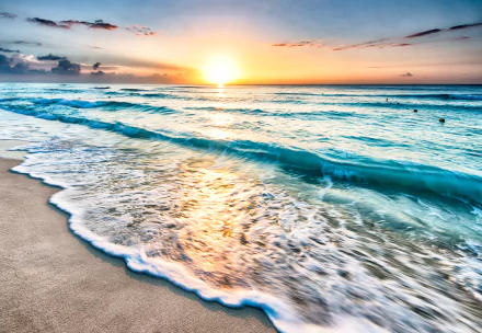 A stunning 4K Ultra HD image of the horizon where the ocean meets the sky at sunset, showcasing vibrant colors and gentle waves lapping on the sandy shore.