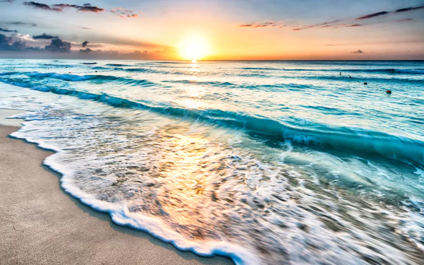 A stunning 4K Ultra HD image of the horizon where the ocean meets the sky at sunset, showcasing vibrant colors and gentle waves lapping on the sandy shore.