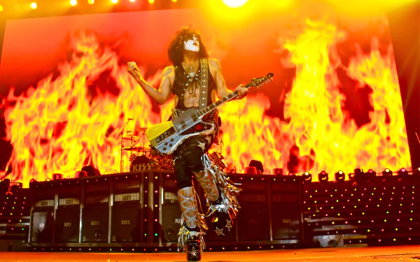HD PC desktop wallpaper: KISS (Band) rock performer in signature face paint and armor playing guitar amid towering stage flames.