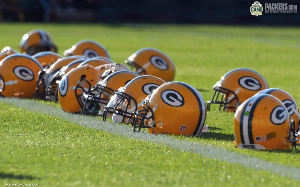 Green Bay Packers helmets lined up on the grass, showcasing team colors and spirit in this HD PC desktop wallpaper and background for sports enthusiasts.