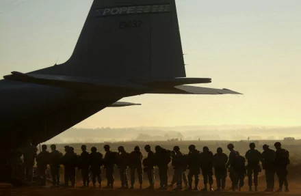Silhouetted soldiers of the United States Army stand in formation by a military aircraft at sunrise, capturing a moment of duty and camaraderie. HD desktop wallpaper.