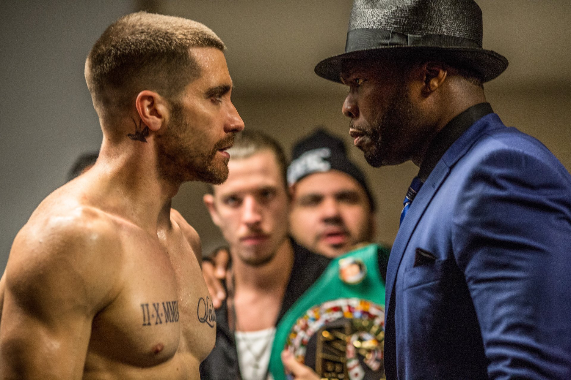 Jake Gyllenhaal shirtless facing a man in a blue suit and hat in a scene from the movie Southpaw, captured in 4K Ultra HD quality.