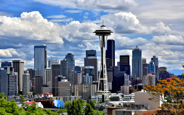 HD desktop wallpaper featuring Seattle's skyline with the iconic Space Needle dominating the cityscape under a cloudy sky.