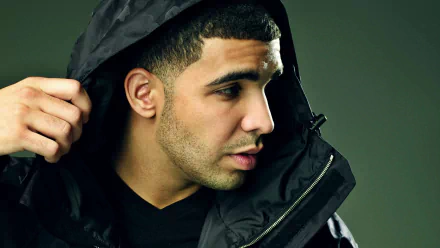 High-definition desktop wallpaper featuring a profile view of a man in a black hooded jacket against a muted background.