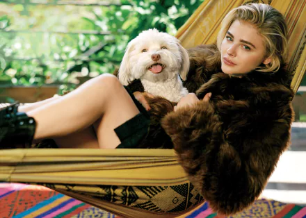 American actress Chloë Grace Moretz with blonde hair and green eyes relaxes in a hammock with a smiling dog, providing a serene HD desktop wallpaper and background.