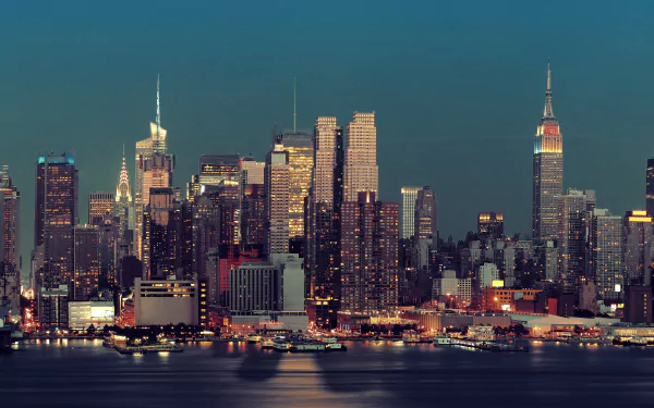 8K Ultra HD PC desktop wallpaper of Manhattan, New York, a man-made skyline at dusk with illuminated high-rises reflecting on the Hudson.