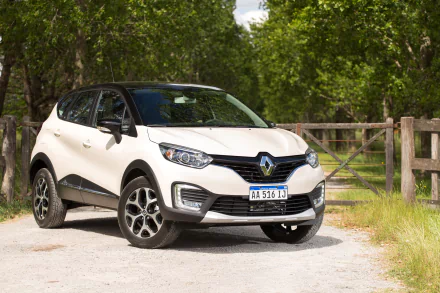 White Renault Captur SUV parked on a gravel road near a wooden fence, surrounded by greenery, presented as an HD PC desktop wallpaper and background.