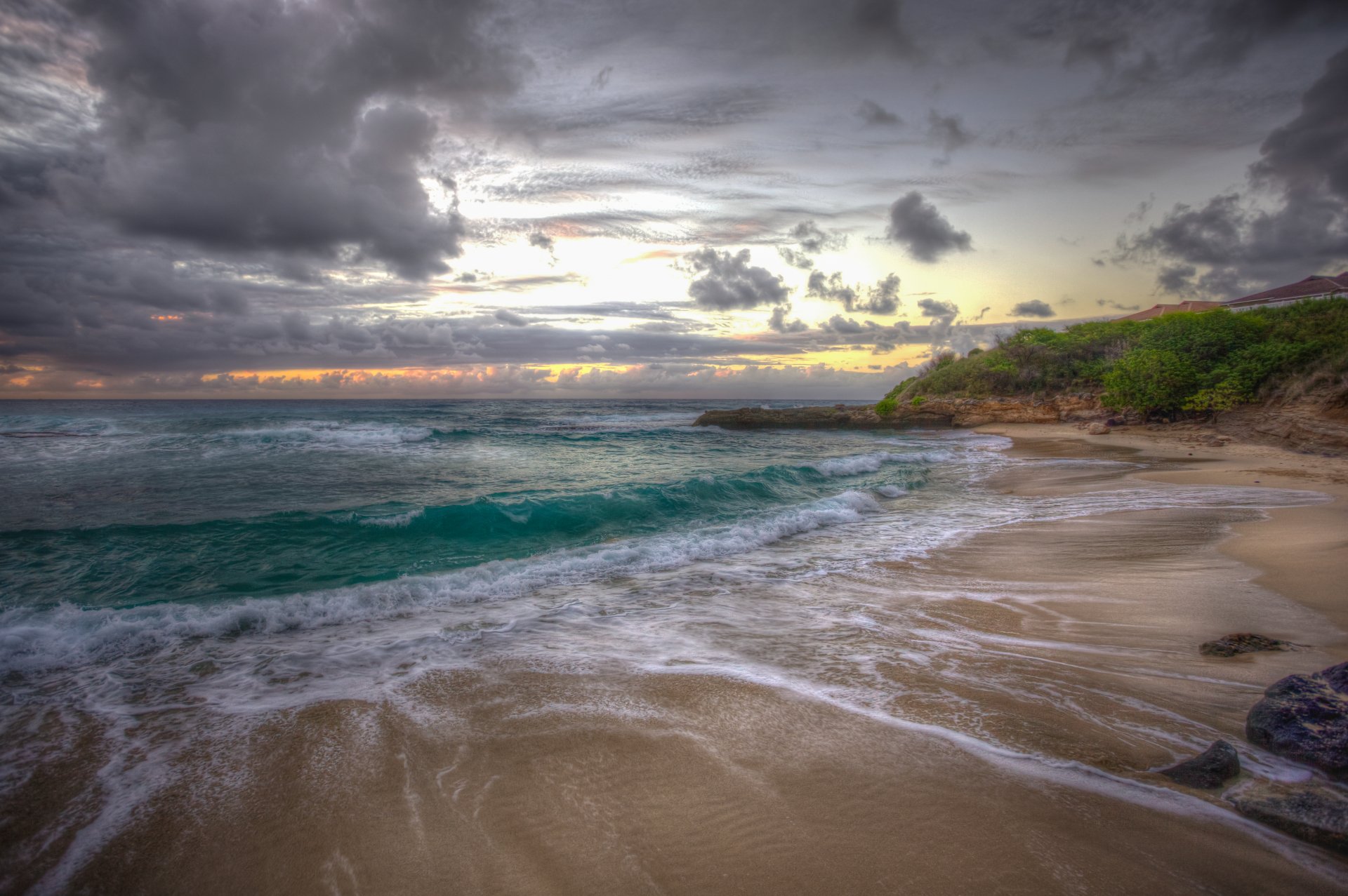 4K Ultra HD desktop wallpaper of a Hawaii beach at sunset, featuring a cloudy sky, ocean waves washing ashore, and lush greenery along the horizon.