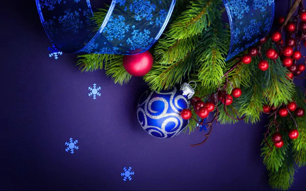 HD desktop wallpaper featuring Christmas ornaments, including a blue bauble, red berries, evergreen branches, and blue ribbon with snowflakes on a dark purple background.