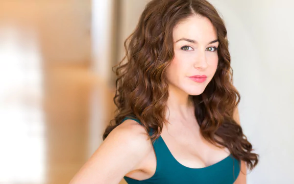 HD desktop wallpaper featuring a poised individual with curly hair and a teal top, providing an elegant background.