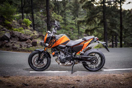 Orange KTM 690 motorcycle parked on a winding forest road, high-detail 4K Ultra HD PC desktop wallpaper/background showcasing the vehicle.