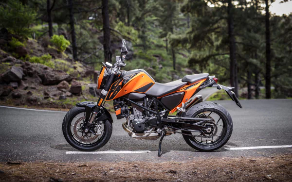 Orange KTM 690 motorcycle parked on a winding forest road, high-detail 4K Ultra HD PC desktop wallpaper/background showcasing the vehicle.