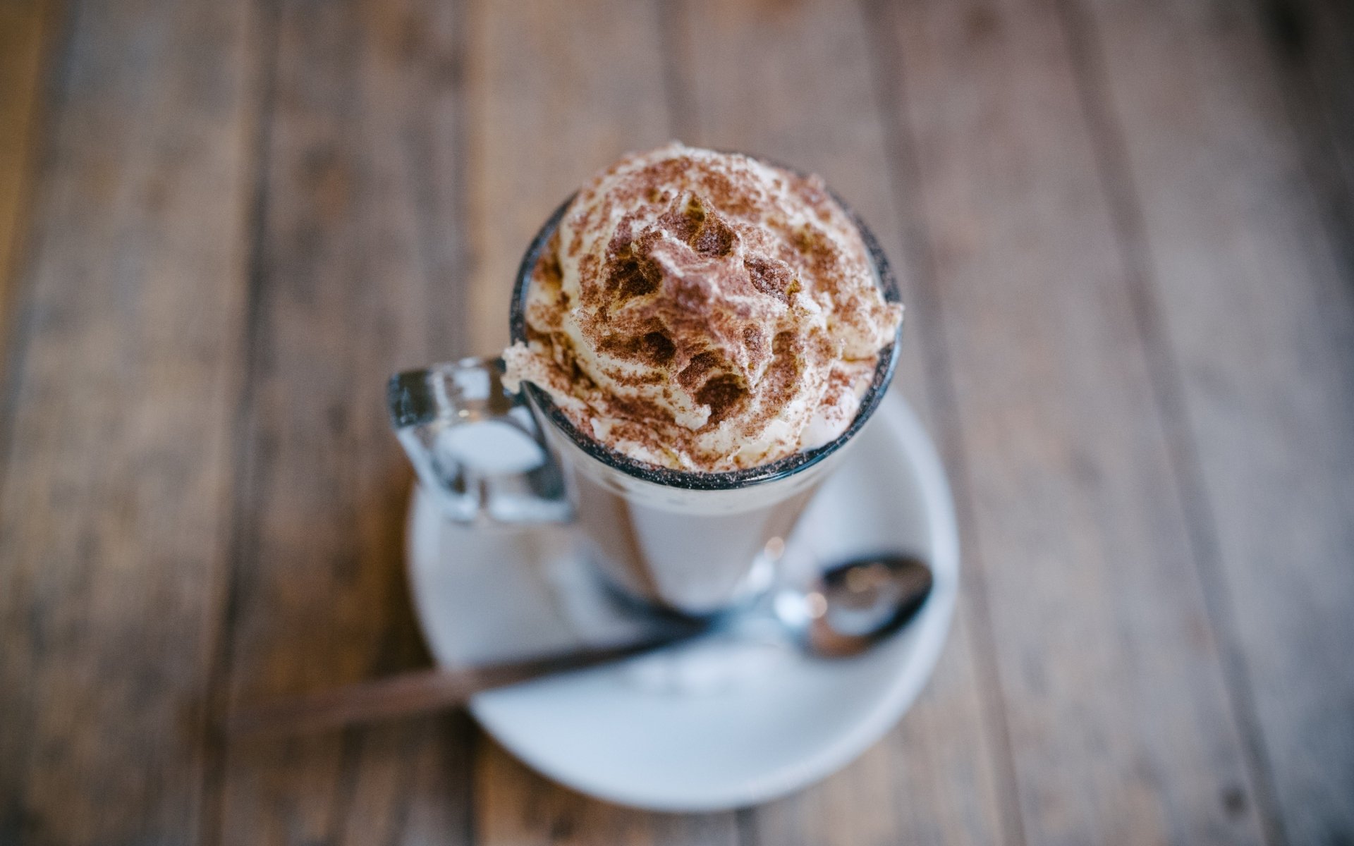 4K Ultra HD PC desktop wallpaper and background: close-up food coffee — glass mug of latte topped with whipped cream and cinnamon on a saucer with a spoon over a rustic wooden table.