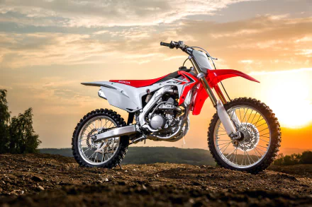 4K Ultra HD wallpaper featuring a red and white Honda CRF motocross motorcycle parked on dirt with a sunset sky in the background.