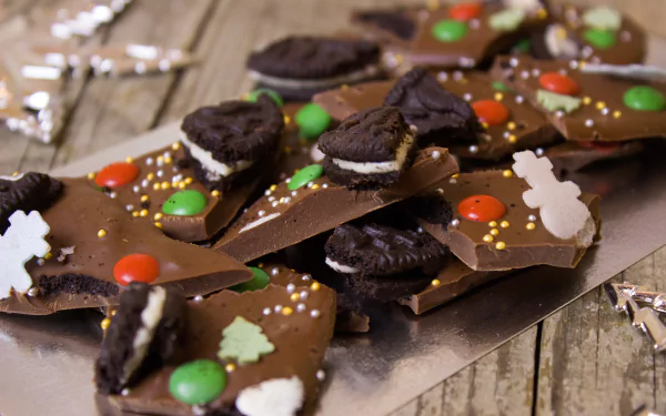 Close-up of chocolate bark topped with broken Oreo cookies, colorful candy-coated sweets, and festive sprinkles, featured as a 4K Ultra HD PC desktop wallpaper background.