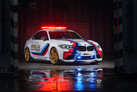 4K Ultra HD PC desktop wallpaper of a BMW M2 Coupe race car vehicle with M-striping, red/blue emergency lights and gold wheels reflected on a wet floor.