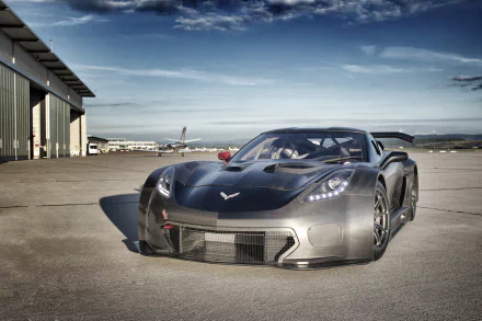 HD desktop wallpaper of a silver Callaway Corvette C7 GT3-R supercar race car (Chevrolet Corvette C7.R) parked on a sunlit airfield.