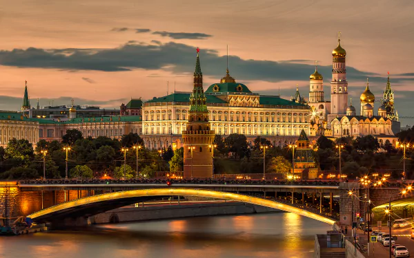 Evening view of Moscow's Kremlin and a lit bridge over the river, showcasing iconic Russian architecture in a vibrant cityscape.