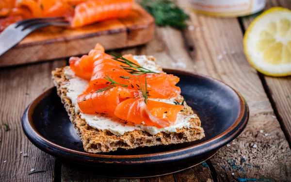 A 4K Ultra HD desktop wallpaper featuring a slice of crisp toast topped with creamy spread and vibrant salmon, garnished with dill, set on a rustic wooden table.