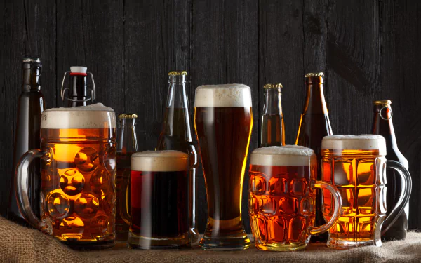 A 4K Ultra HD desktop wallpaper featuring a variety of beer bottles, mugs, and glasses filled with amber and dark beer against a dark wooden background.